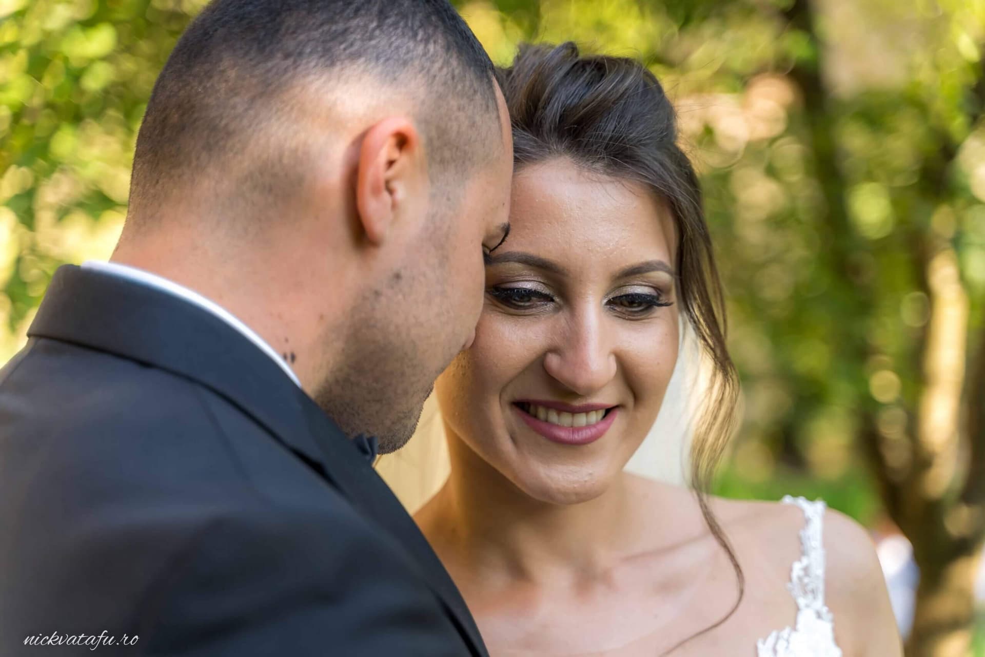 Mire și mireasă zâmbind emoționați, într-un moment intim, fotografie de nuntă în natură.