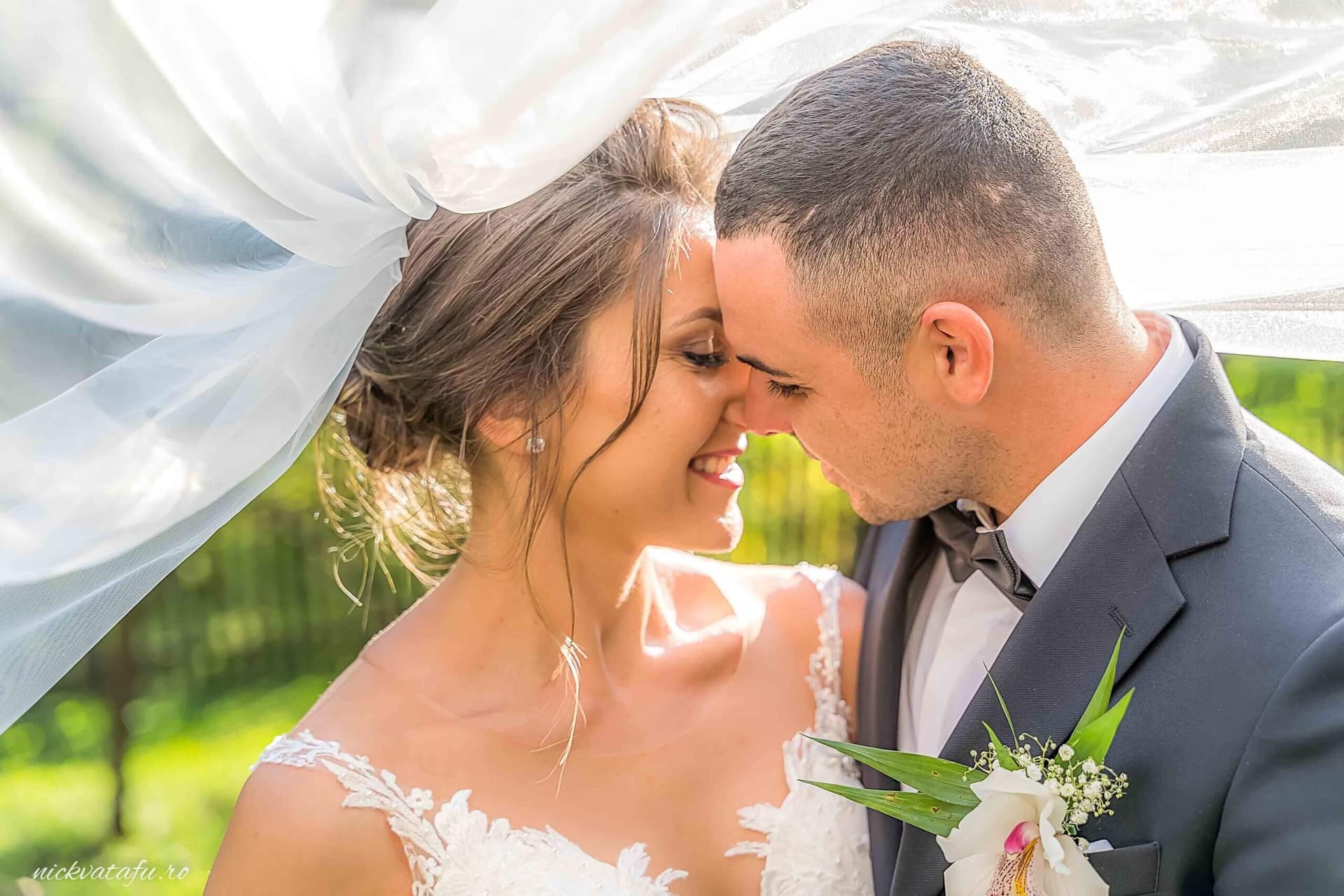 Mire și mireasă în moment de intimitate sub voal, fotografie de nuntă plină de emoție și fericire.