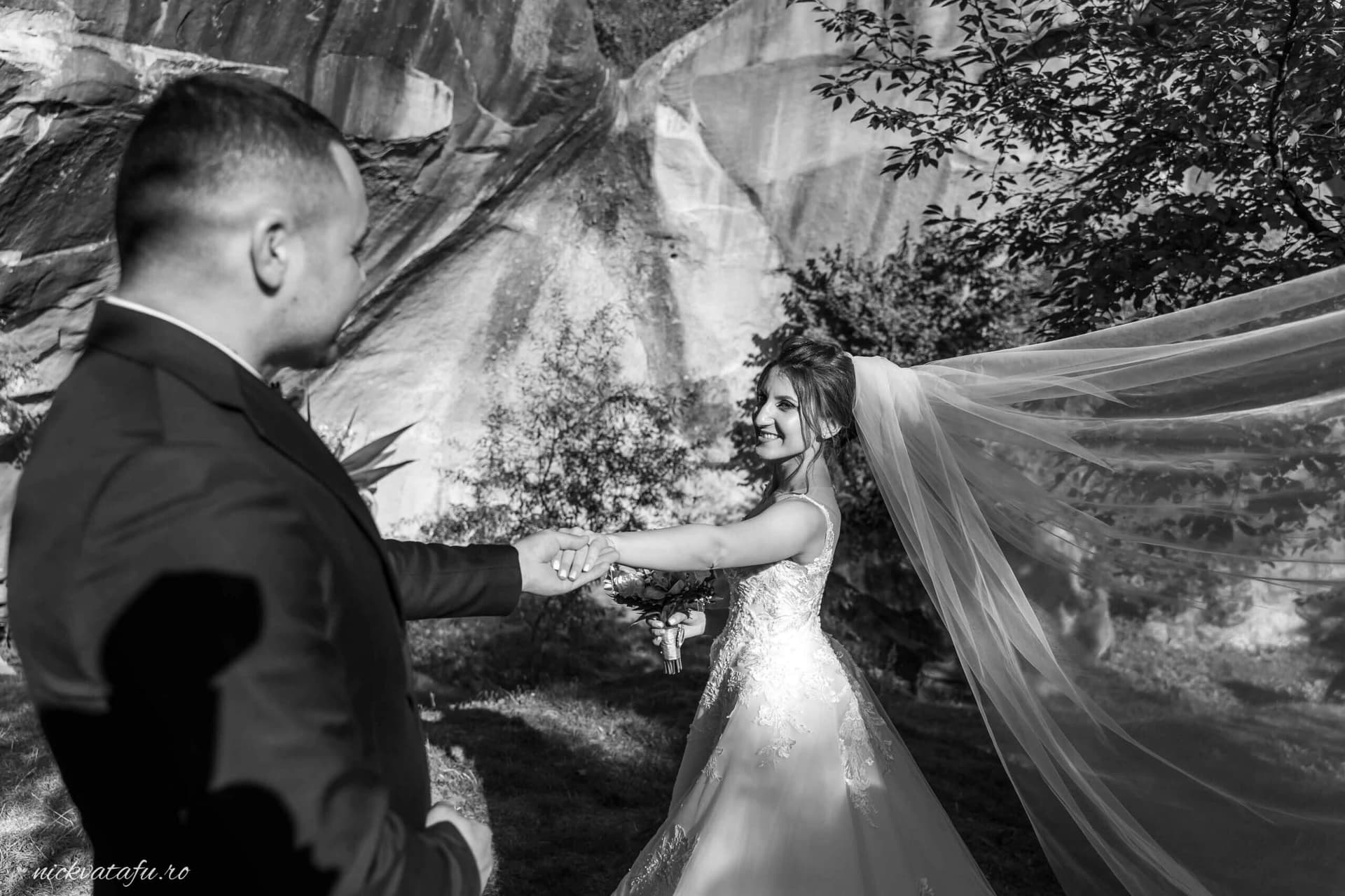 Mire și mireasă zâmbind unul către altul, într-un cadru romantic, fotografie de nuntă în natură.