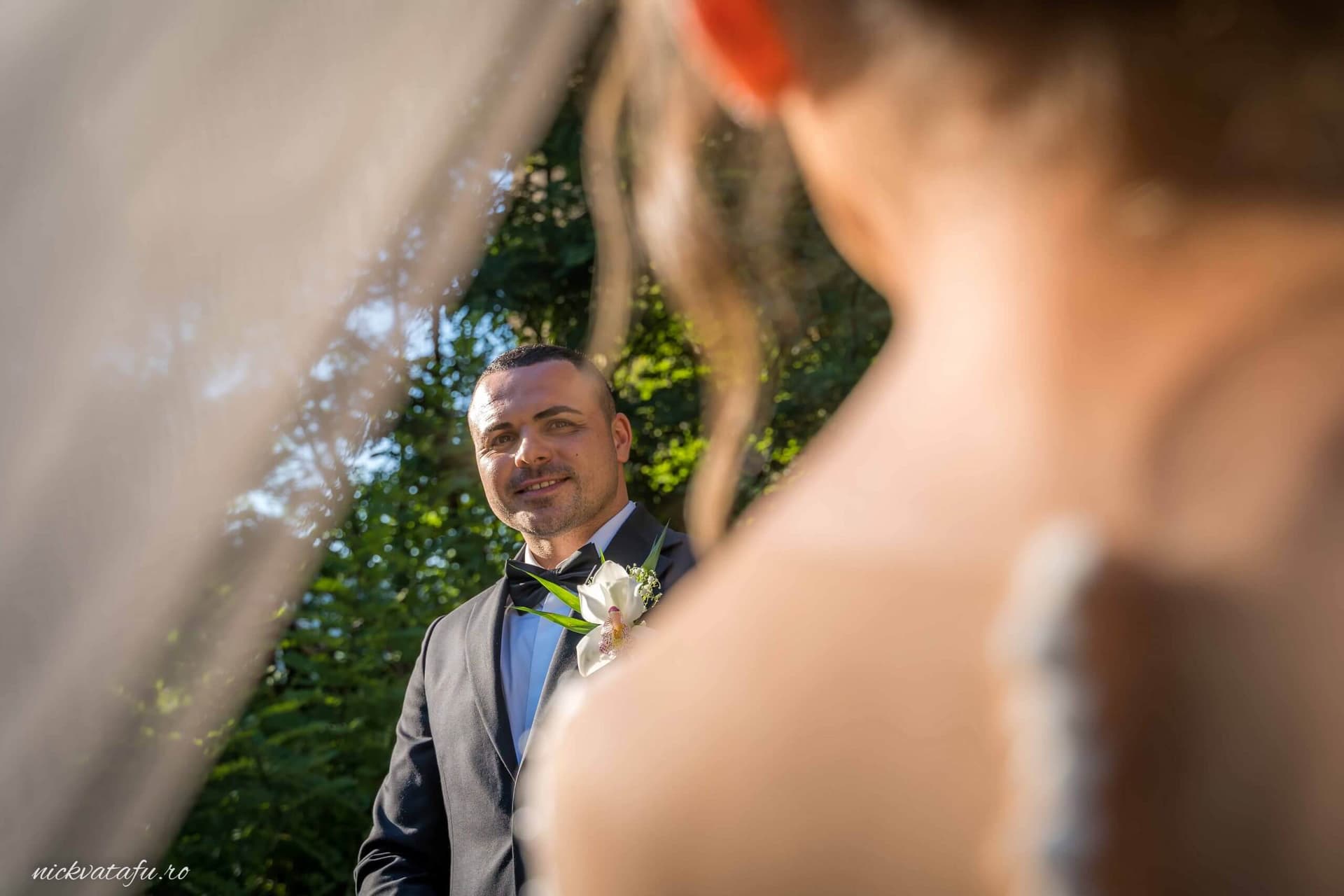 Mireasă privindu-l cu emoție pe mire, în lumina naturală a unei ceremonii de nuntă.