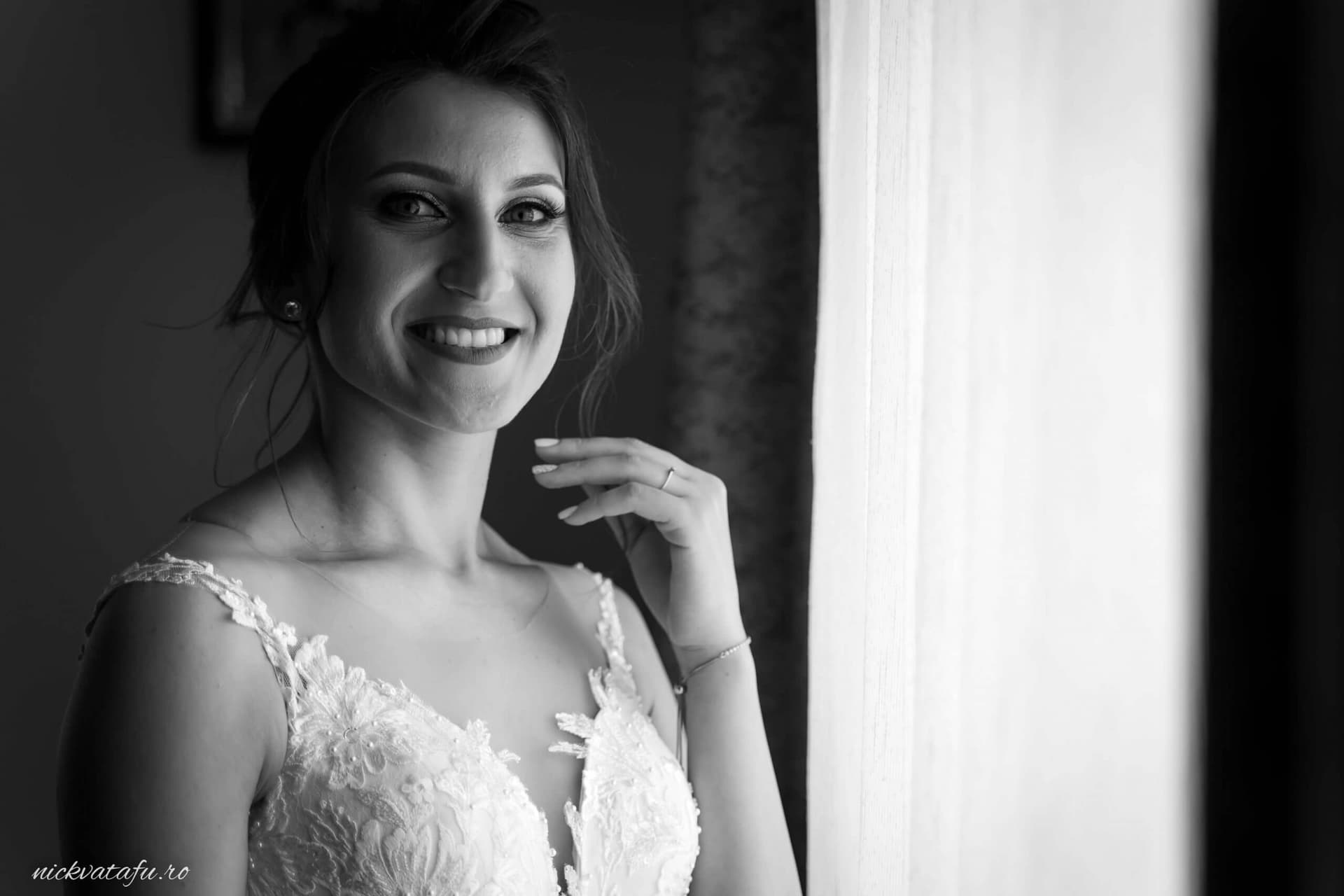 Mireasă zâmbitoare în fața feronierului, pregătită pentru marele eveniment, fotografie nuntă elegantă.