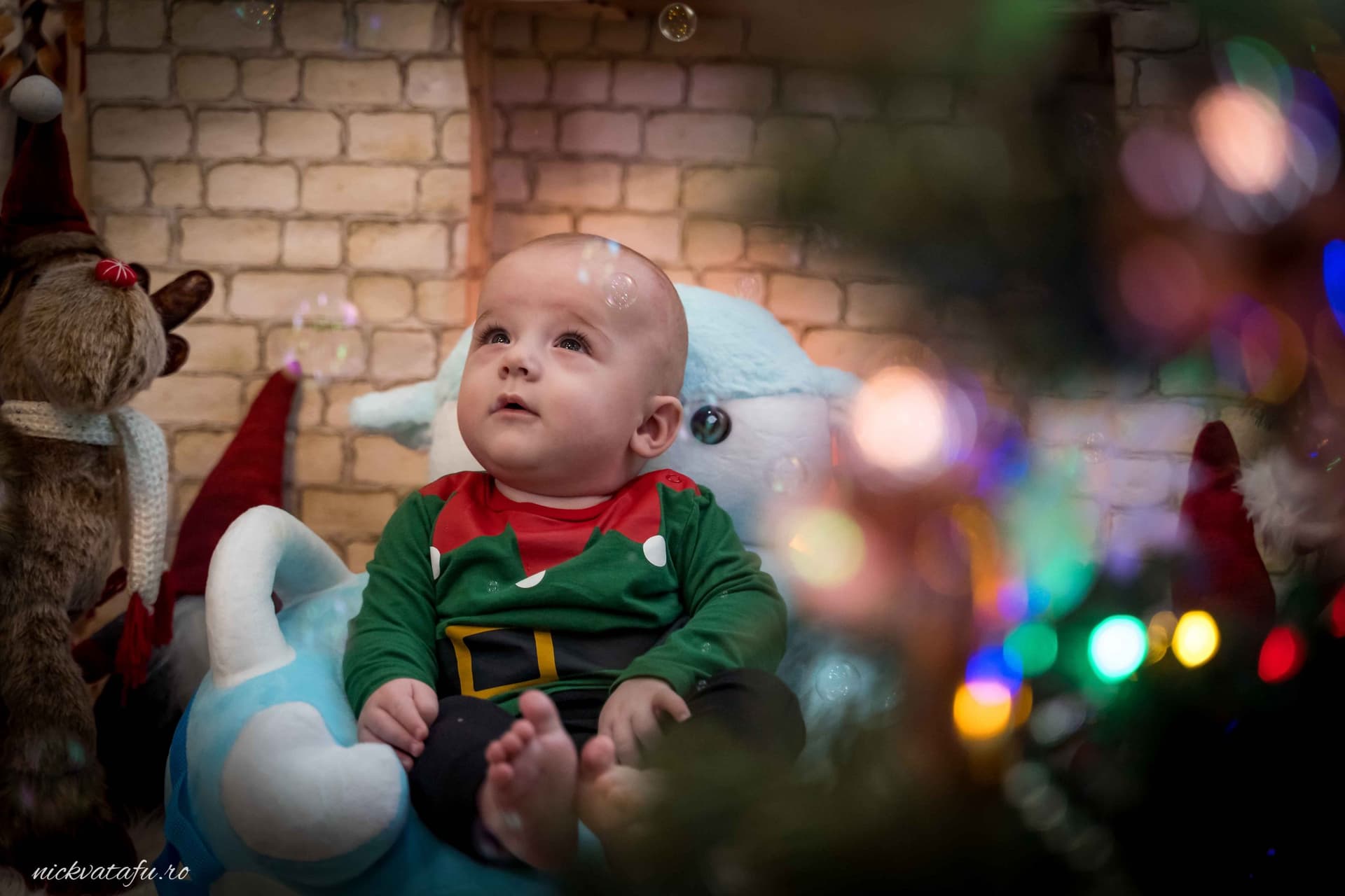Băiețel îmbrăcat în costum de elf, zâmbind și admirând bradul de Crăciun, fotografie emoționantă de sărbătoare.
