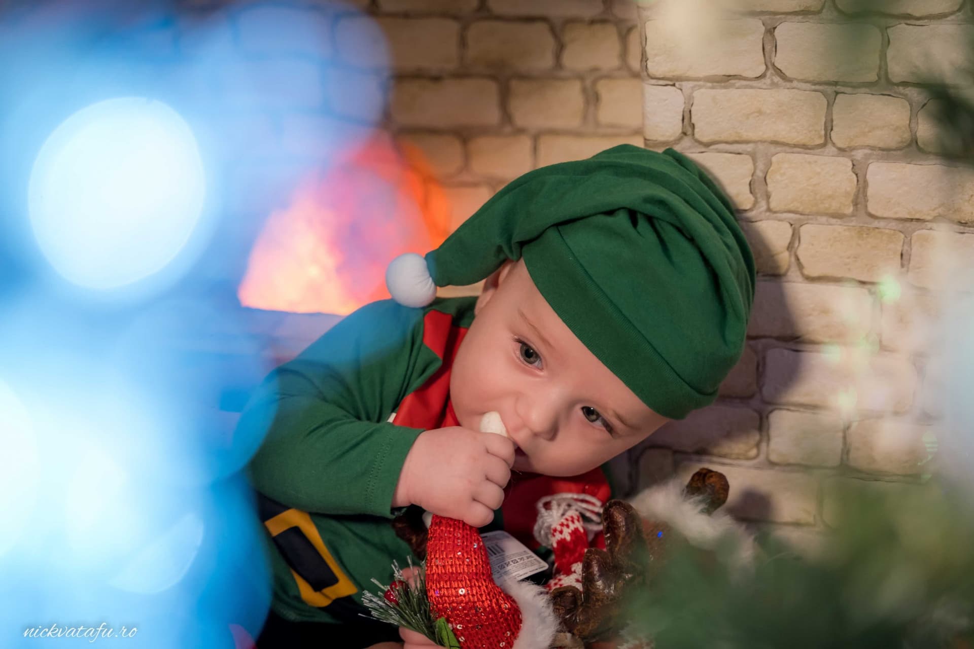 Băiețel îmbrăcat ca un elf, jucându-se cu o jucărie, în decorul festiv al Crăciunului, plin de emoție și bucurie.