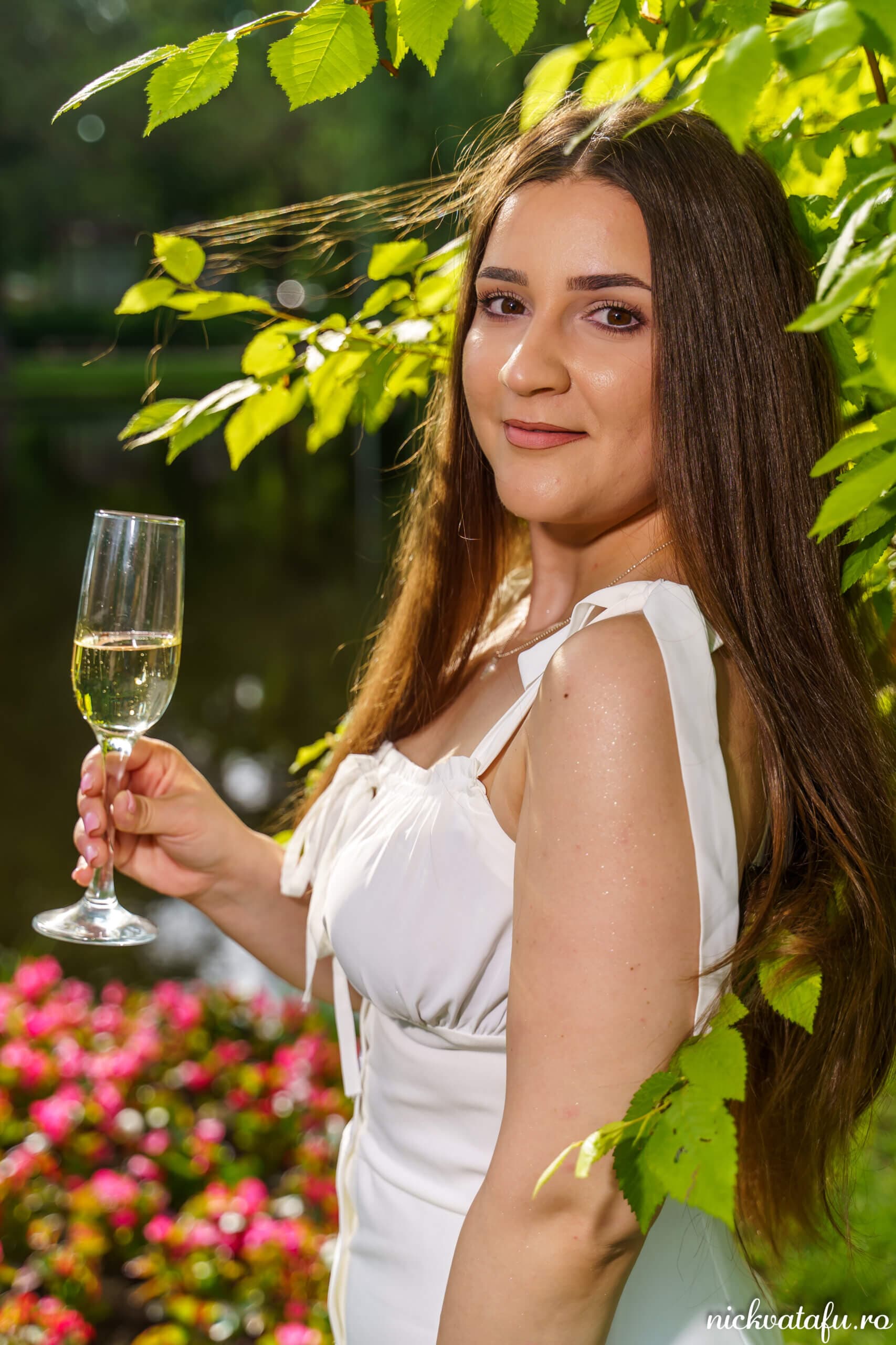 Mireasă elegantă, cu un pahar de șampanie, zâmbind în grădina plină de flori, fotografie nuntă plină de emoție.