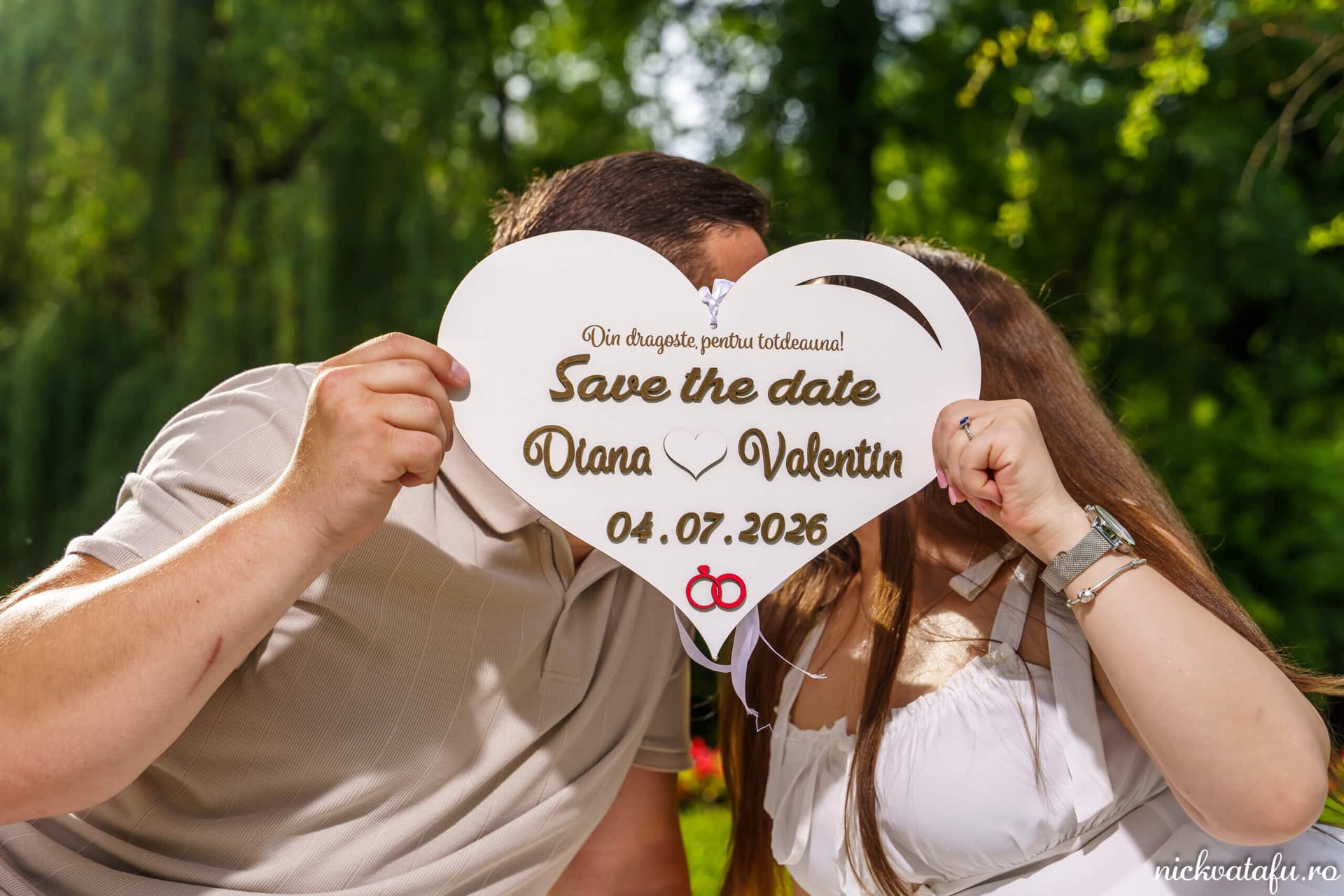 Cuplu fericit ținând un panou „Save the date” în natură, fotografie nuntă plină de emoție și iubire.